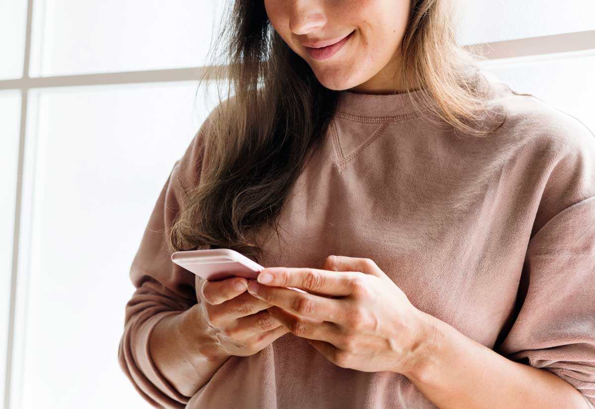 Woman using a smartphone to engage on social media as part of a small business digital marketing strategy