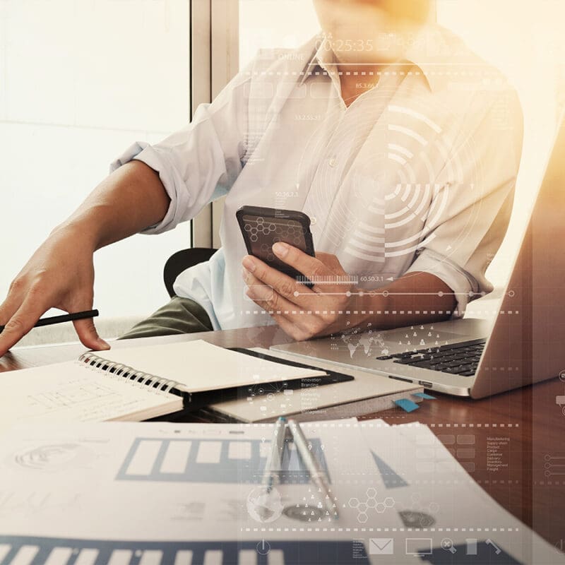 Marketing professional reviewing data analytics on a smartphone while planning strategy at a modern workspace