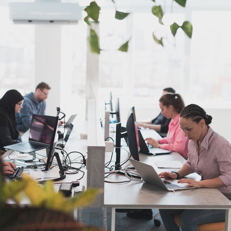 Team of professionals working on laptops in a modern office creating blog and digital content