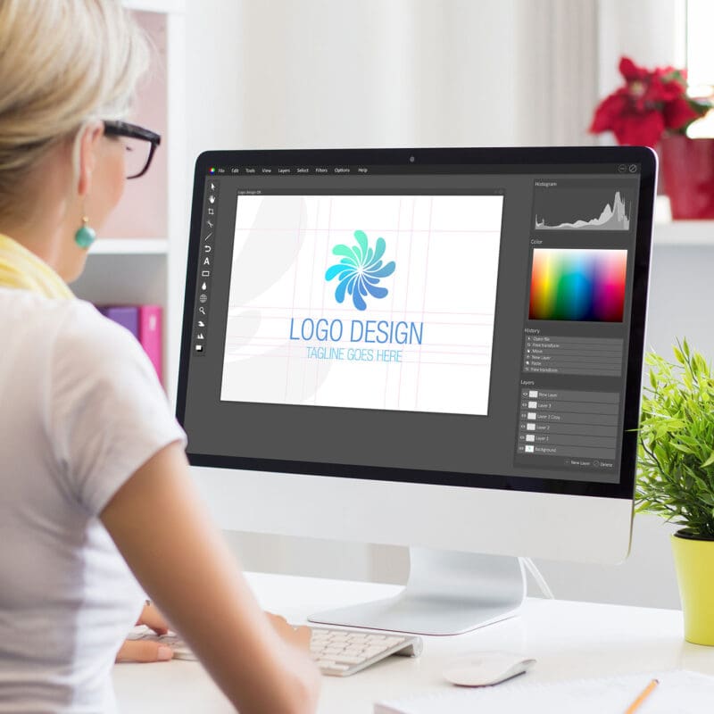 Graphic designer creating a custom logo design on desktop computer in a bright creative workspace