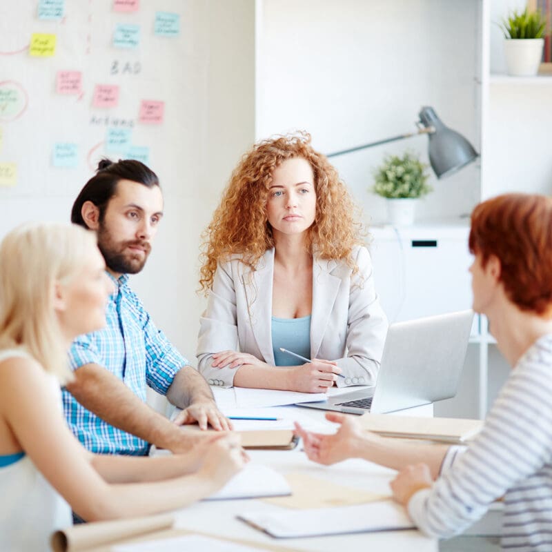 Marketing professionals collaborating around a table during a strategy meeting in a modern office