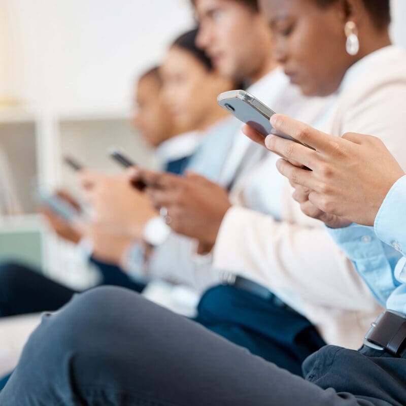 Group of professionals using smartphones while seated in a modern office waiting area