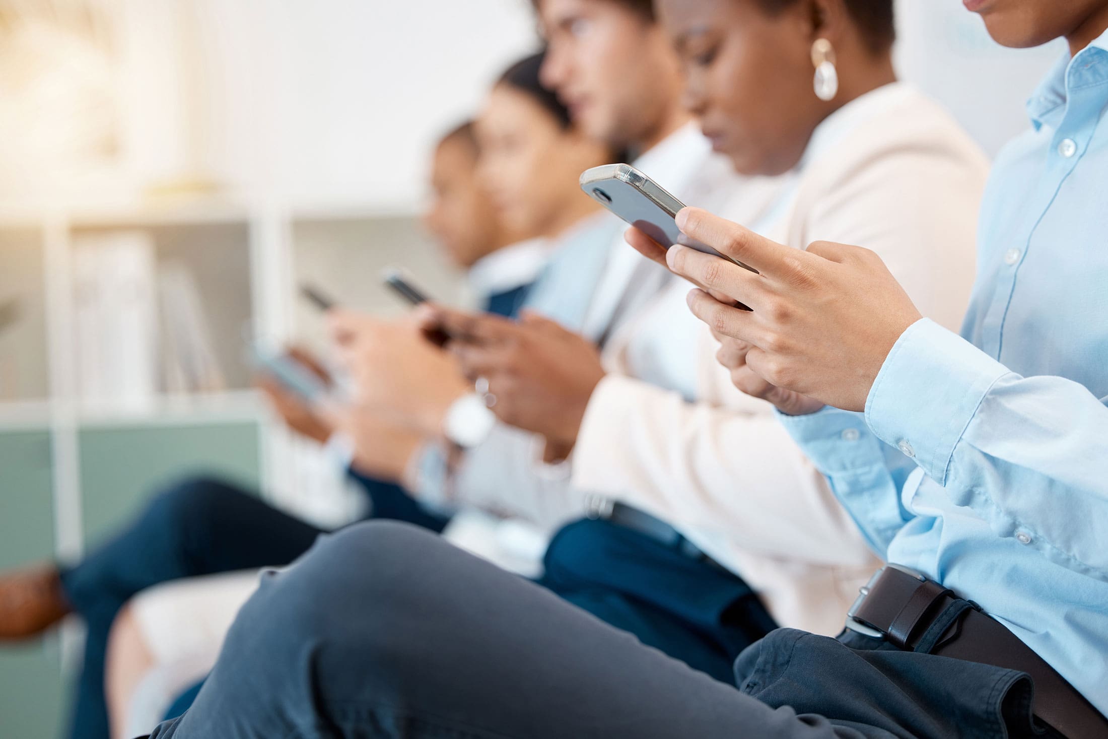 Group of professionals using smartphones while seated in a modern office waiting area