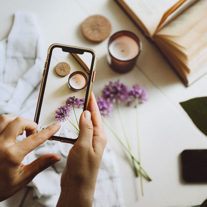Person photographing styled flowers and decor with a smartphone for social media content