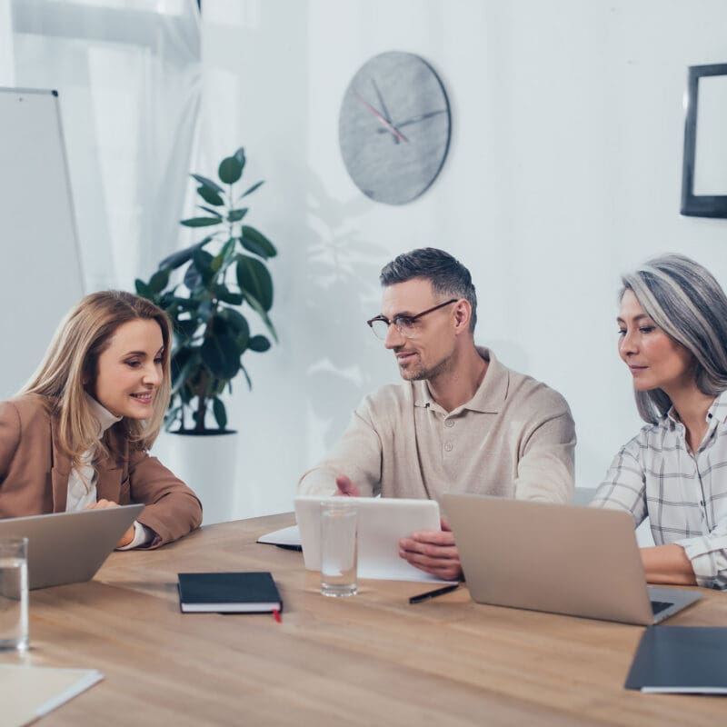 Three Colleagues working together on their laptops and iPads in the office
