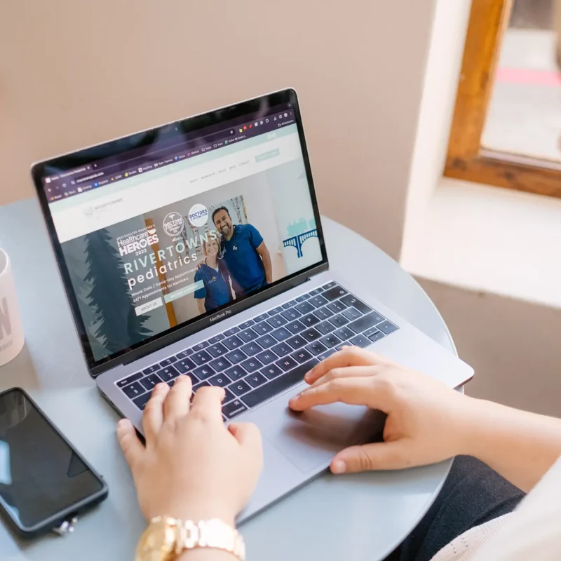 Designer reviewing pediatric healthcare website on laptop during professional web design workflow