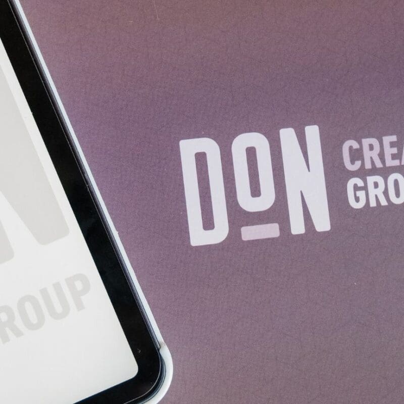 A folder and ipad both displaying the benefits of Branding with Don Creative Group's Logo