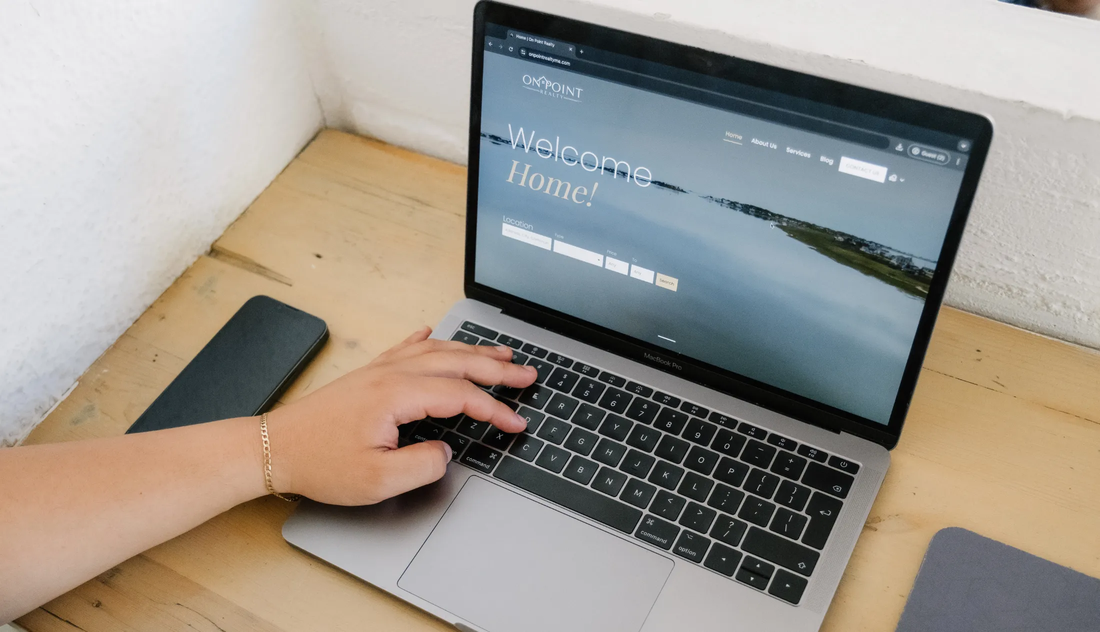 a person, not fully showing, scrolling through On Point Realty's homepage of their website that Don Creative Group created