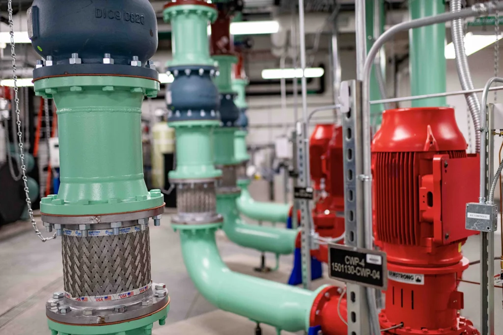 Industrial Mechanical Room With Pumps and Piping System Industrial mechanical room with green piping, valves, and red pump motors, showing a clean, well-maintained infrastructure system supporting building operations
