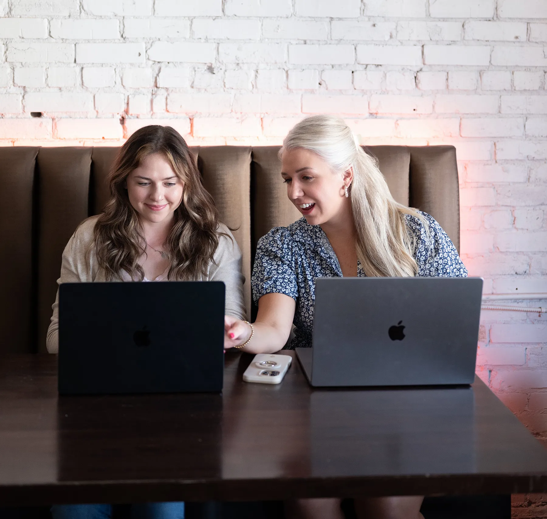 Two professionals collaborating on website design strategy while reviewing content on laptops
