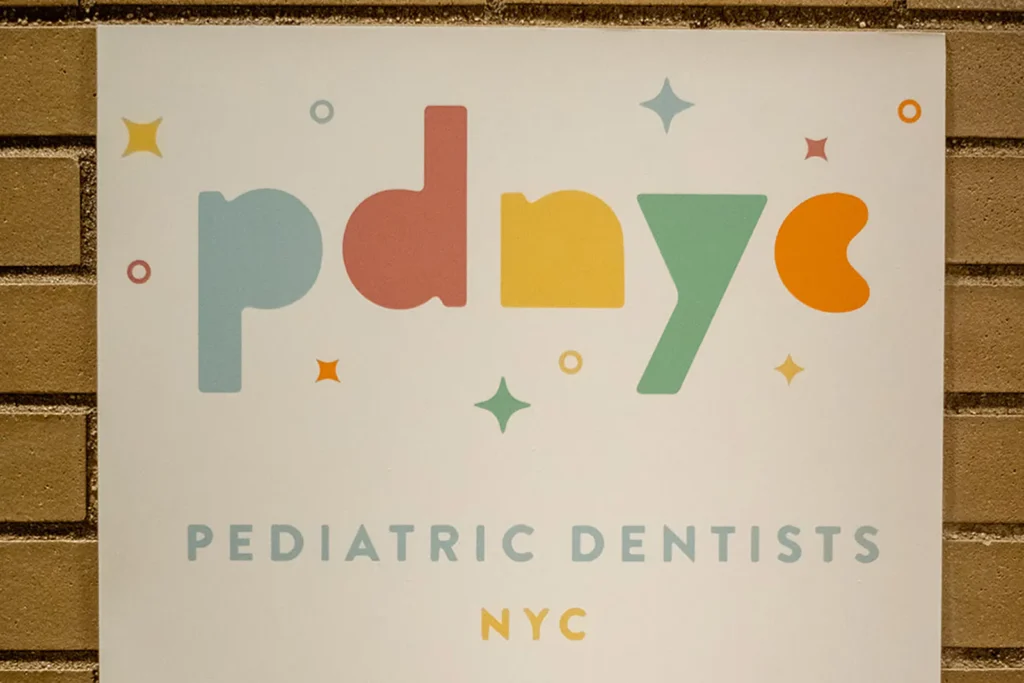 PDNYC Pediatric Dentists logo signage in New York City PDNYC Pediatric Dentists logo sign displayed on a brick wall with colorful child-friendly lettering