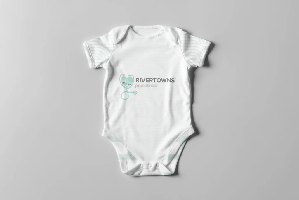 Rivertowns Pediatrics branded baby onesie with heart stethoscope logo