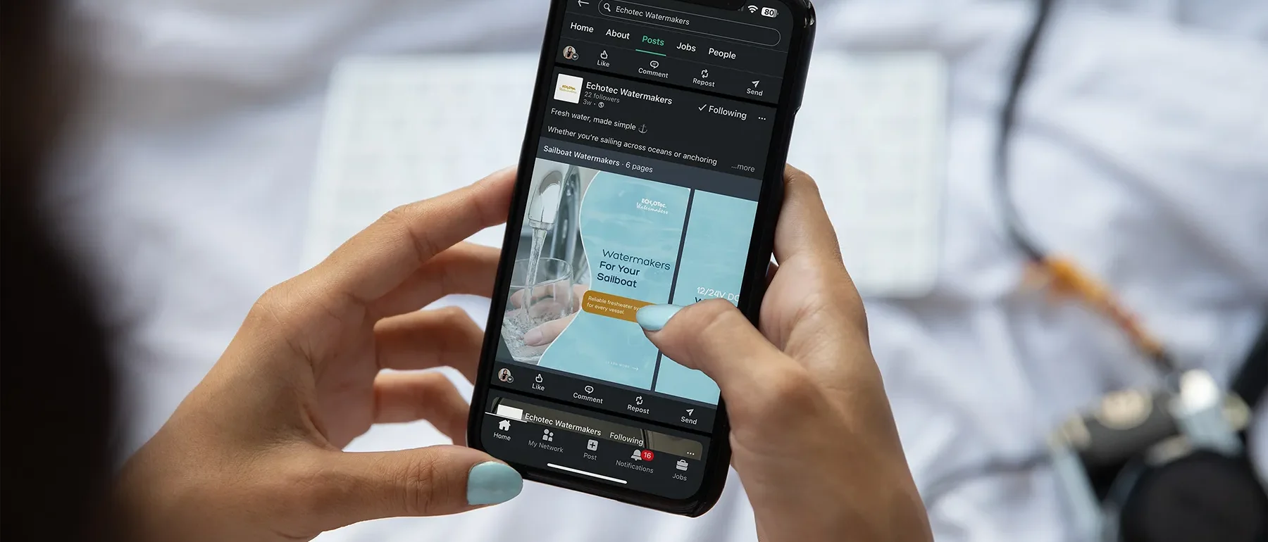 Person holding a smartphone viewing ECHOTec Watermakers social media post about sailboat watermakers