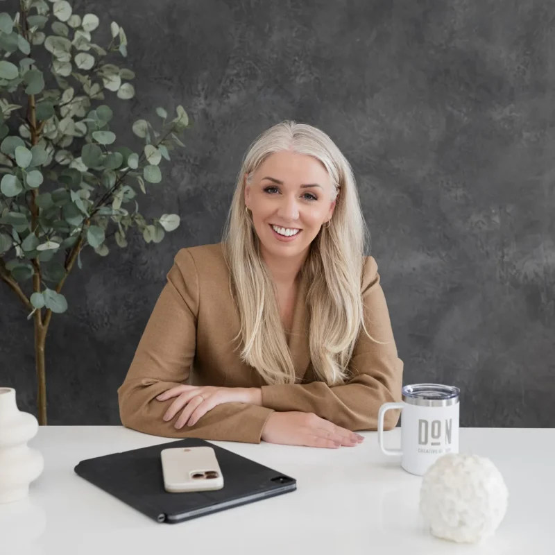 Smiling professional woman seated at a desk in a modern studio office setting